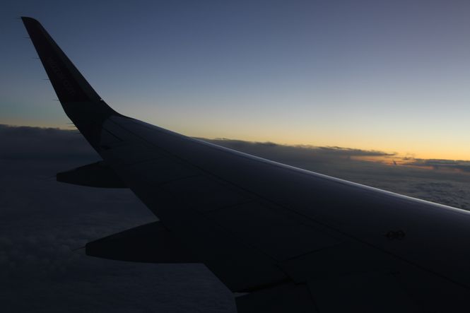 skrzydło samolotu Wizz Air na tle zachodu słońca nad chmurami